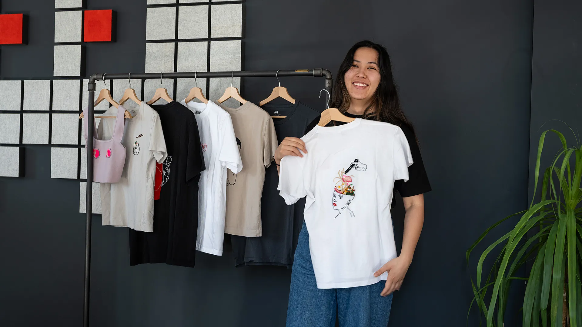 Desiree hält ihre bestickten T-Shirts hoch
